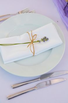 Elegant table setting for wedding engagement Easter dinner with white ceramic plates cotton napkin tied with twine lavender flowers candles. Provence style.