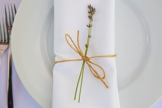 Elegant table setting for wedding engagement Easter dinner with white ceramic plates cotton napkin tied with twine lavender flowers candles. Provence style.