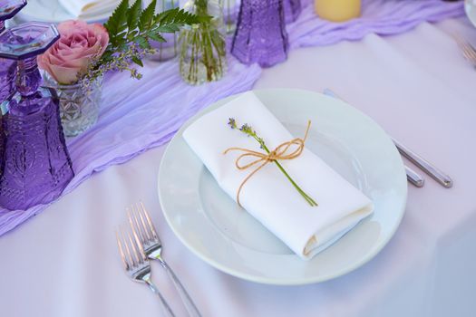 Elegant table setting for wedding engagement Easter dinner with white ceramic plates cotton napkin tied with twine lavender flowers candles. Provence style.