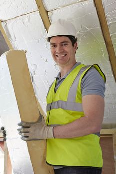 Builder Fitting Insulation Boards Into Roof Of New House