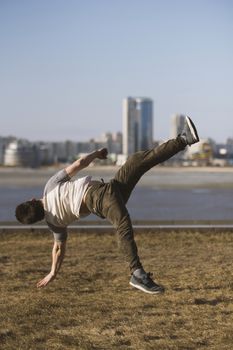 Young man parkour sportsman performs acrobatic jumps in front of skyline, telephoto shot