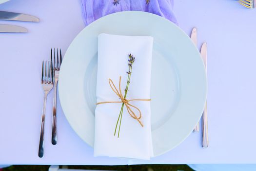 Elegant table setting for wedding engagement Easter dinner with white ceramic plates cotton napkin tied with twine lavender flowers candles. Provence style.