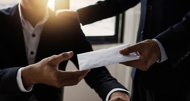 Close up hand of manager giving money bonus in paper envelope to happy office worker,congratulating employee with increasing of salary or promotion as new position