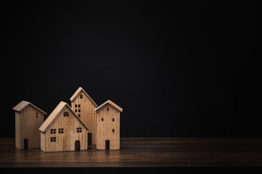 real estate concept, small wooden house or home on table with black background 