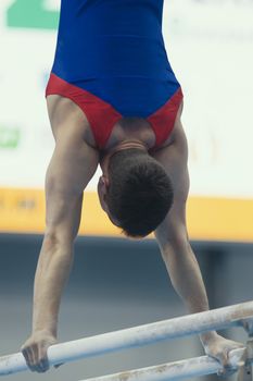 Young man gymnasts competing on the bar at the championship, close up