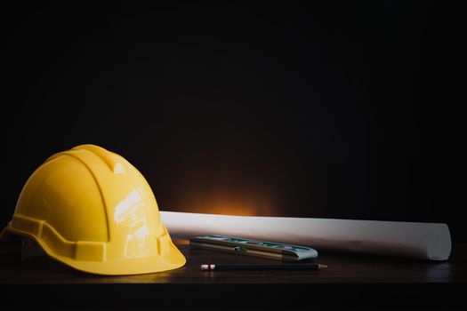 real estate, property and construction project concept, engineer's tools  with helmet on table in dark background 