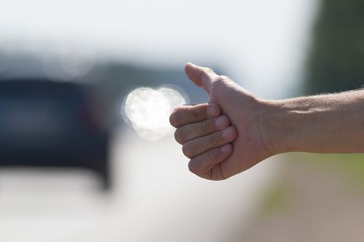 Hand of a man who honks to passing cars, hitchhiking trip, close up