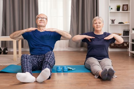 Older people who have a healthy lifestyle doing sport in living room. Old person healthy lifestyle exercise at home, workout and training, sport activity at home on yoga mat.