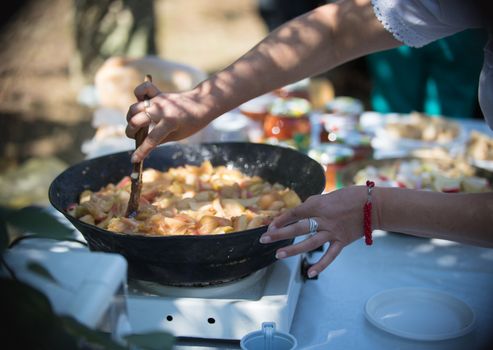 A woman prepares Apple jam on a holiday outdoors in the summer, close up