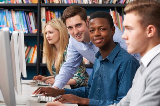 Tutor With Group Of Teenage Students Using Computers