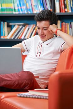 Male Teenage Student With Laptop Working In Library