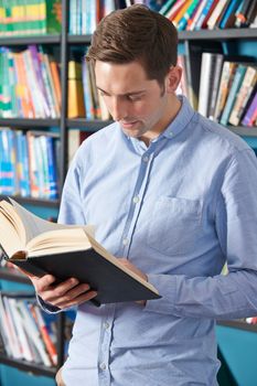 University Student Reading Textbook In Library