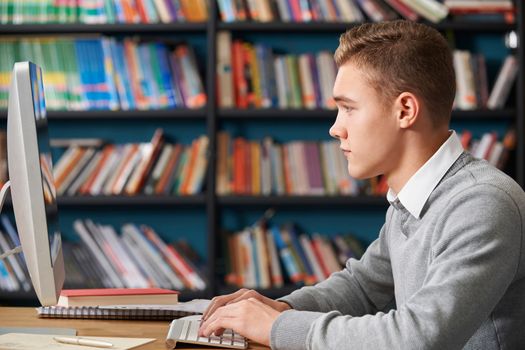 Male Teenage Student Working At Computer In Library