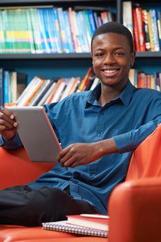 Male Teenage Student Using Digital Tablet In Library