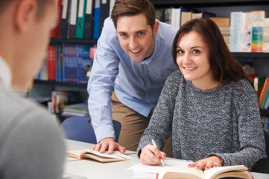 Teacher Helping Female Teenage Pupil In Class