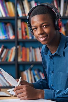 Teenage Student Wearing Headphones Whilst Working In Library