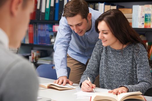 Teacher Helping Female Student In Classroom