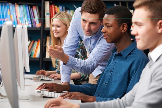 Tutor Working With Group Of Teenage Students Using Computers