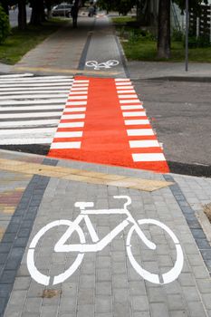 Cycling path with a symbol of bike on a ground through avtomobile road. Bike path in a modern city