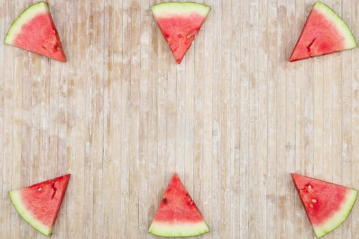 Triangular slices of watermelon that form geometric games for copy space on a light wooden background