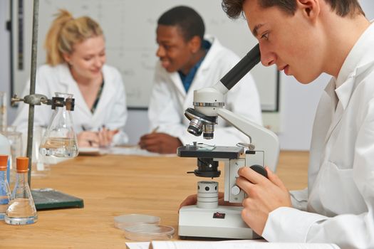 Teenage Students In Science Class Using Microscope