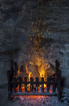 Old fashioned open log fireplace in with flames and sparks