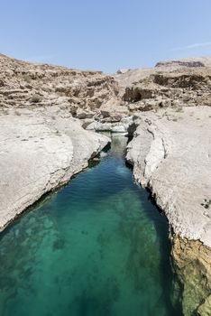 River (with turquoise water) and pool in the canyon of Wadi Bani Khalid, a tourist attraction and famous destination of the Sultanate of Oman, Middle East