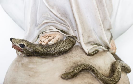 The Virgin Mary crushing the serpent of original sin with his foot. Defocused blurry background.