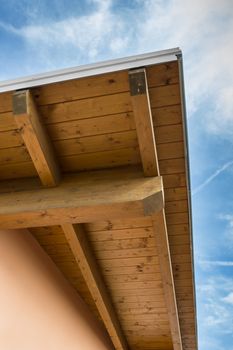 Corner of house with wooden beams against blue sky.