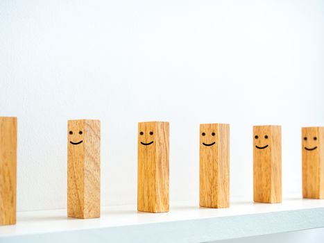 Social Distancing concept. Row of smiley face wooden dominoes with distance space on shelf on white background.