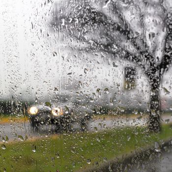 Rain on the car glass, wet day, shot through a windscreen, focusing on the rain droplets.