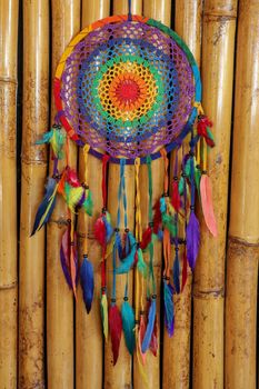 Beautiful multicolored handmade dreamcatcher on natural bamboo background.