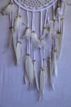 Closeup of white dream catcher a small white hoop decorated with feathers and beads.