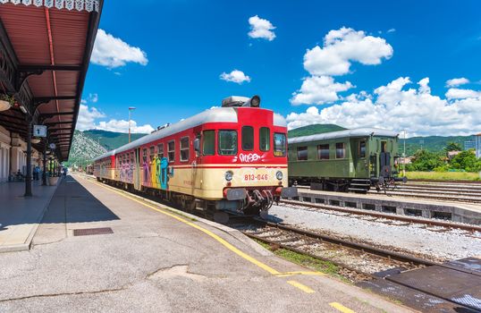 Nova Gorica (Gorizia) - June 2016, Slovenia: Wide angle view of trains on tracks at the old train station, view from the platform, summer day with blue sky and cumulus clouds