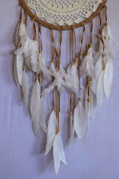 Closeup of white dream catcher a small white hoop decorated with feathers and beads.