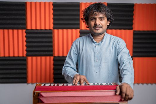 Young musician playing Indian music instrument Harmonium in studio