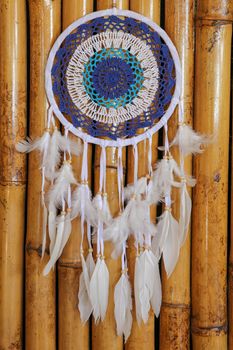 Blue Dreamcatcher with feathers and beads isolated on a wodden background.