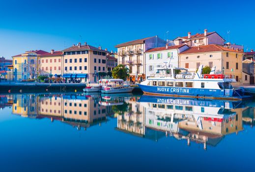 Grado - December 2015, Friuli Venezia Giulia region, Italy: Colored residential buildings and boats are mirror reflected in the sea water