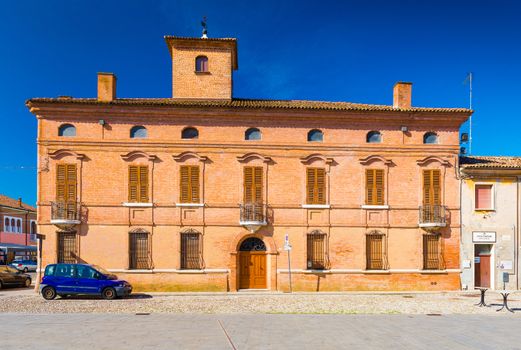 Comacchio - October 2017, Italy: View of the old historical building made of red brick in the historic center of Comacchio. Blue car parked near the old building