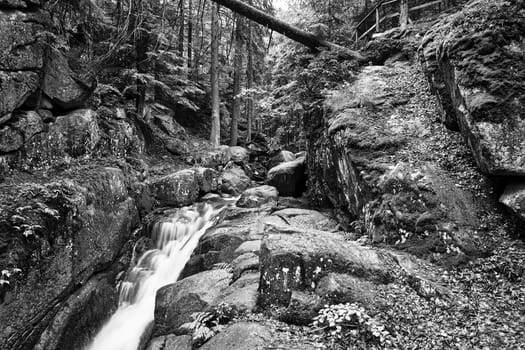 Rocks, boulders and waterfall in the forest in the Giant Mountains in Poland, black and white