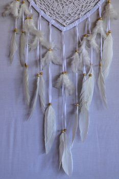 Closeup of white dream catcher a small white hoop decorated with feathers and beads.