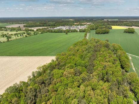 Landscape with a forest, meadows and fields and a small village in the background, aerial view from a height of 100 meters, Germany