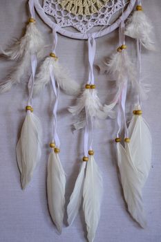 Closeup of white dream catcher a small white hoop decorated with feathers and beads.