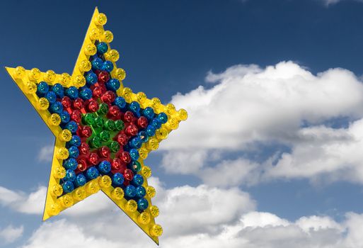 Large colorful star of differently colored lamps exempted in front of a blue sky with clouds, illustration
