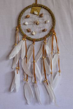 sea shell decoration. dream catcher. Handmade pink native american dream catcher on background of rocks and lake. Tribal elements, feathers, shells, lace