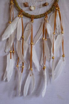 Closeup of white dream catcher a small white hoop decorated with feathers and beads.