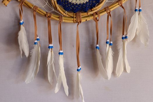 Closeup of white dream catcher a small white hoop decorated with feathers and beads.