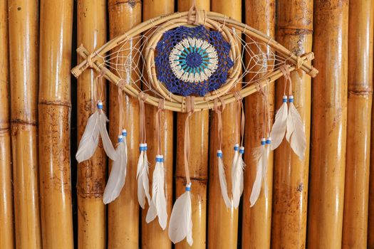 god eye of providence dreamcatcher with white feathers on a wodden background.