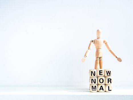 New Normal, words on wooden alphabet cube and wooden figure on white background with copy space. New normal life after covid-19 pandemic concept.