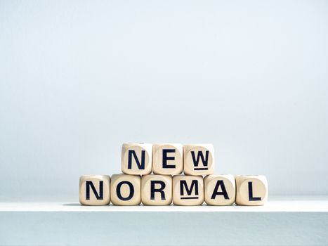 Close-up New Normal, words on wooden alphabet cube on shelf on white background. New normal after covid-19 pandemic concept.